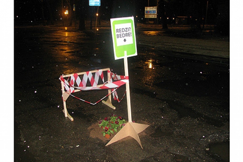 Protestējot pret ielu slikto stāvokli, ar ziediem rotā bedres (papildināts)